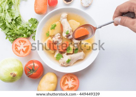 A picture of a bowl of traditional chicken soup served in a bowl over vegetable background