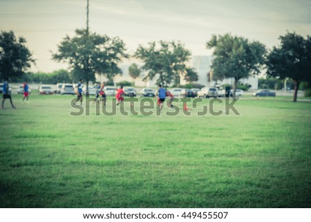 Blurred abstract motion of African American people playing football on green soccer pitch of the park at sunset with warm light at Houston, Texas. Urban healthy lifestyle concept. Vintage filter look.