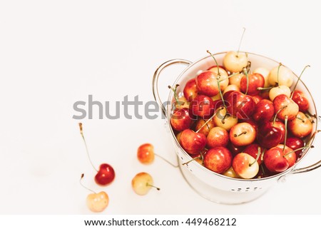 Ripe fresh sweet cherries in a white bowl colander over white background in matte film finish