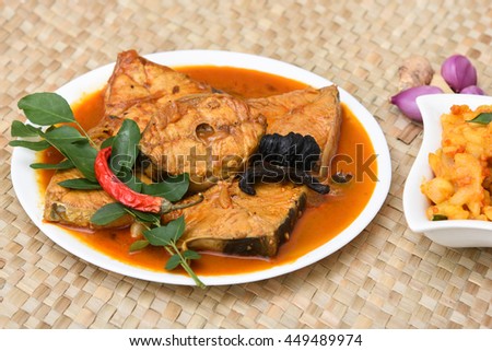 Top view of spicy and hot king fish curry with cooked tapioca / cassava root Kerala India. Barracuda Fish curry with green chili, green curry leaf, coconut milk and mango Asian cuisine.