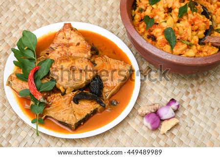 Top view of spicy and hot king fish curry with cooked tapioca / cassava root Kerala India. Barracuda Fish curry with green chili, green curry leaf, coconut milk and mango Asian cuisine.