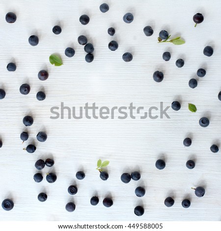 flat layout of the forest blueberries scattered on the edges against a background of pale wood top view / picture frame berry