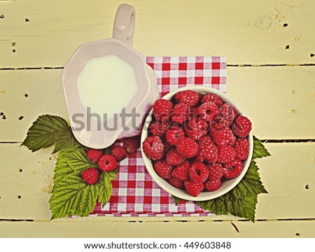 Pink jug with milk plate raspberries on a yellow wooden background 1