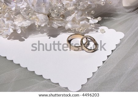 wedding rings on a blank white card with white beads and flowers -  copy space