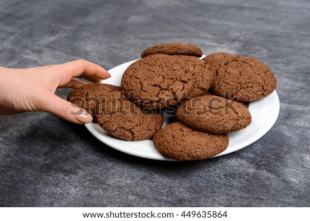 Picture of hands holding chocolate cookies over wooden background