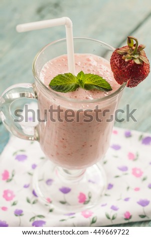 A glass of strawberry milk shake with fresh strawberries and mint.
