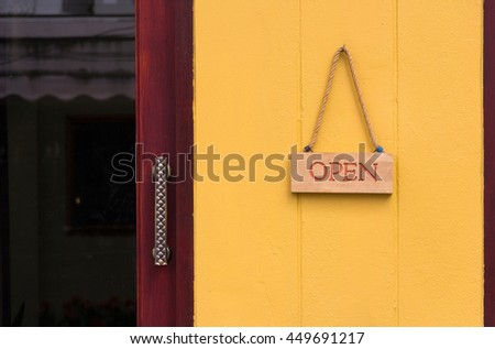 wooden open sign hang on yellow wall at the shop