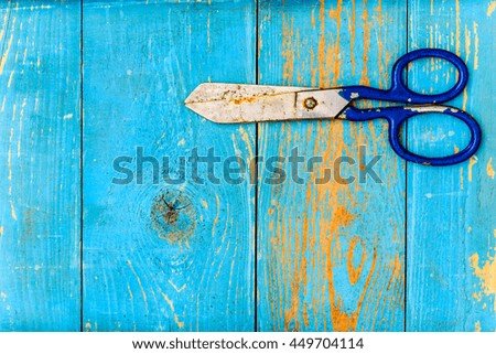 Rusty and old scissors on old wooden table covered with blue paint. View from above
