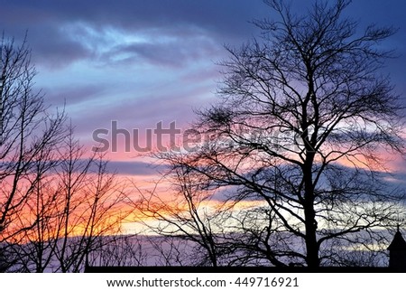 Silhouetted with trees and dramatic colorful sunset and sunrise bright colors beautiful sky. Autumn landscape.

Colorful sunset with trees in foreground.