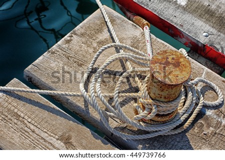 Closeup of wooden pier. Closeup of mooring bollard with white rope in marina. Beautiful seascape background, horisontally picture. Sailing. Mooring and water transport concept.