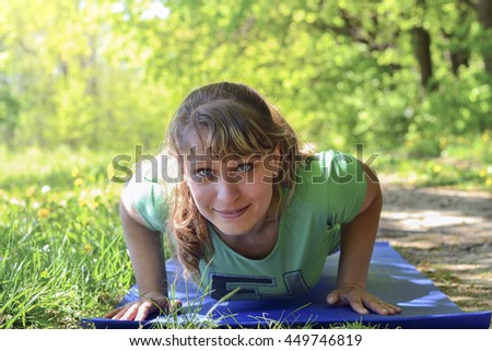 Pretty woman doing yoga exercises in the park. Young woman doing yoga outside in natural environment