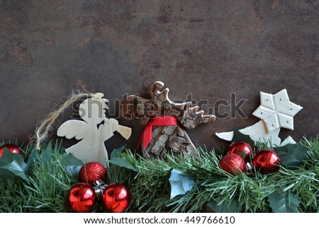 Christmas composition with pine tree branch garland, wooden deer, homemade toys( angel) and red glass balls on grunge brown background. Text space image.