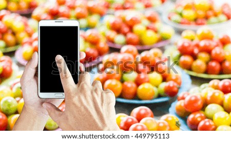 Man use mobile phone,  blur image of tomatoes on a plate as background.