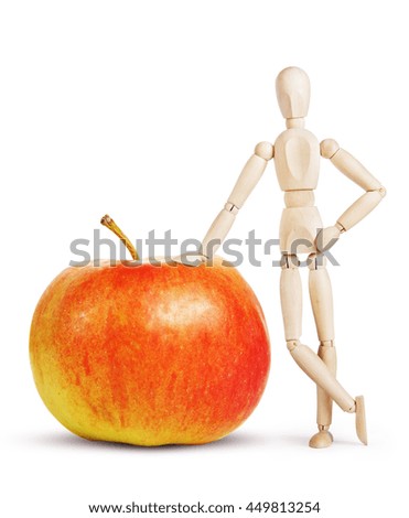 Man leans on a huge red apple. Abstract image with a wooden puppet