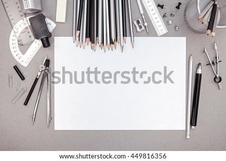 office workspace with blank paper, pencils and various drawing tools, top view