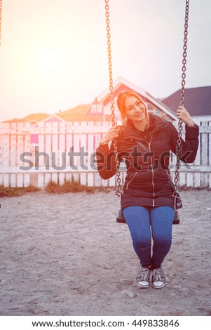 hipster beautiful woman sitting on a swing with sunset sky blurred background.freedomand vintage concept