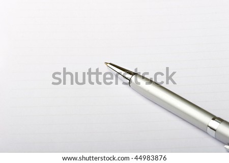 Metal roller pen on a note pad paper sheet