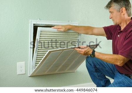 Professional repair service man or diy home owner removing a dirty air filter on a house air conditioner so he can replace it with a new clean one. Royalty-Free Stock Photo #449846074