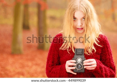 Portrait of pretty woman in fall forest park with old vintage camera. Gorgeous young girl passionate photographer. Autumn winter photography.