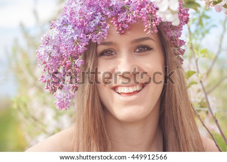 beautiful young woman smiling in the apple garden with flower wreath on a warm summer day