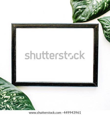 Empty photo frame and green leaves isolated on white. flat lay, top view
