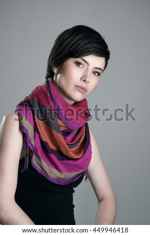 Gorgeous short hair brunette beauty wearing colorful shawl around neck looking at camera over gray studio background
