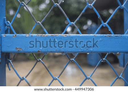 close up blue iron bar and wire of fence with water drop of rain