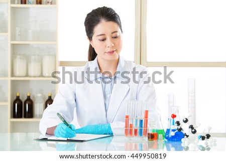 Asian female scientist Recording her data is important on clipboard in laboratory