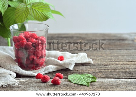 Raspberry on a wooden table in a glass of rustic style background