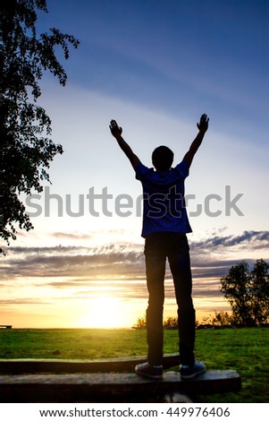 Happy Man Silhouette with Hands Up on the Sunset Background
