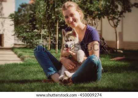 Beautiful woman with husky outdoors.Woman with smiling siberian husky dog, sitting on a sunny day, on a walk with dog. Photo toned.