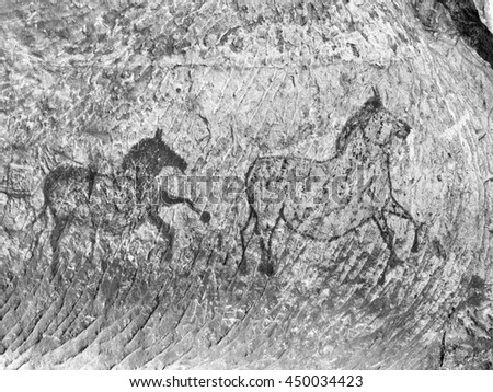 Abstract children art in sandstone cave. Black carbon paint of horses on sandstone wall, copy of prehistoric picture. 