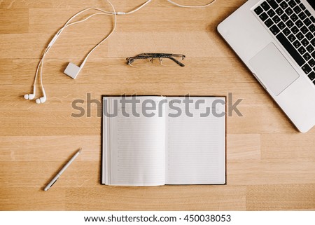 Modern workspace with laptop, notebook, glasses, headphones and pen on wooden background. Top view, flat lay