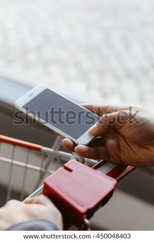 Closeup on order via smart phone application, shop cart department store mall background