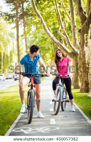 Cycling young couple. In the park. Beautiful bicycle lane