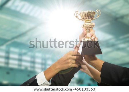 Businessman team holding award trophy for show their victory. Royalty-Free Stock Photo #450103363
