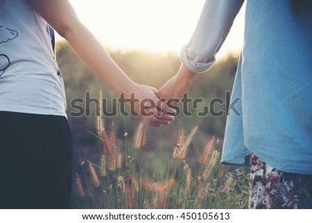 A young couple holding hands. In Nature sunrise