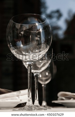 Wine goblets in the shadows in perspective with reflection in black and white.