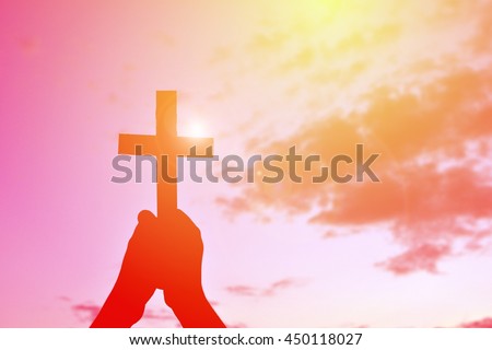 Silhouette hand holding jesus and cross at sunset