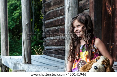 little girl sitting on a porch of a wooden house