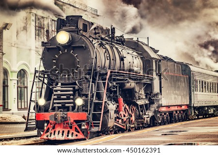 Retro steam train departs from the station. Royalty-Free Stock Photo #450162391