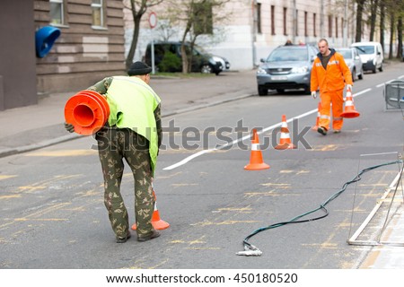 Road construction workers on city street during traffic lines markings works