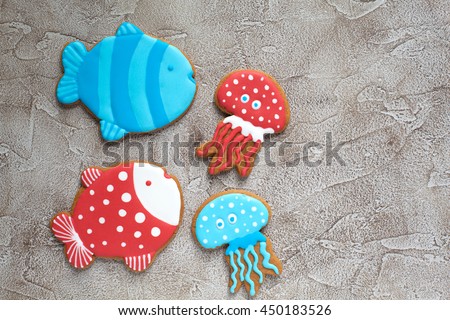 Homemade homemade gingerbread cookie in the shape of colorful fish and jellyfish on a wooden background. Space for text and selective focus.