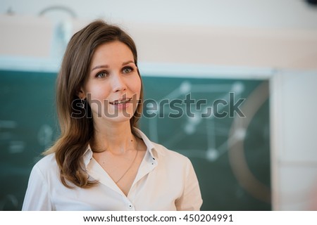 happy teacher standing in front of black board