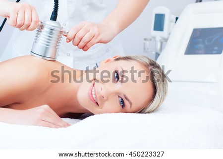 Hardware cosmetology. Picture of happy young woman getting cavitation procedure in a beauty parlour.