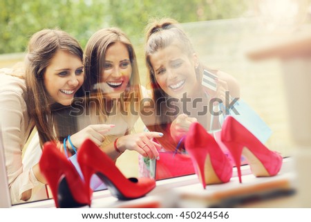 Picture presenting group of girlfriends shopping for shoes in the city with credit card