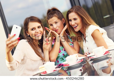 Picture presenting group of friends chatting in cafe and taking selfie