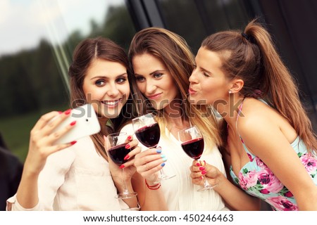 Picture presenting happy group of friends with red wine taking selfie