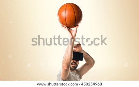 Man playing basketball using VR glasses over ocher background