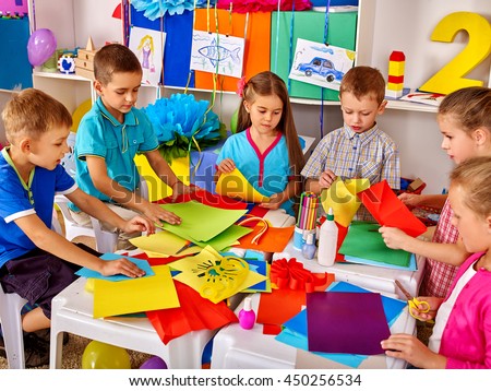 Group kids are making something out of colored paper in primary school.